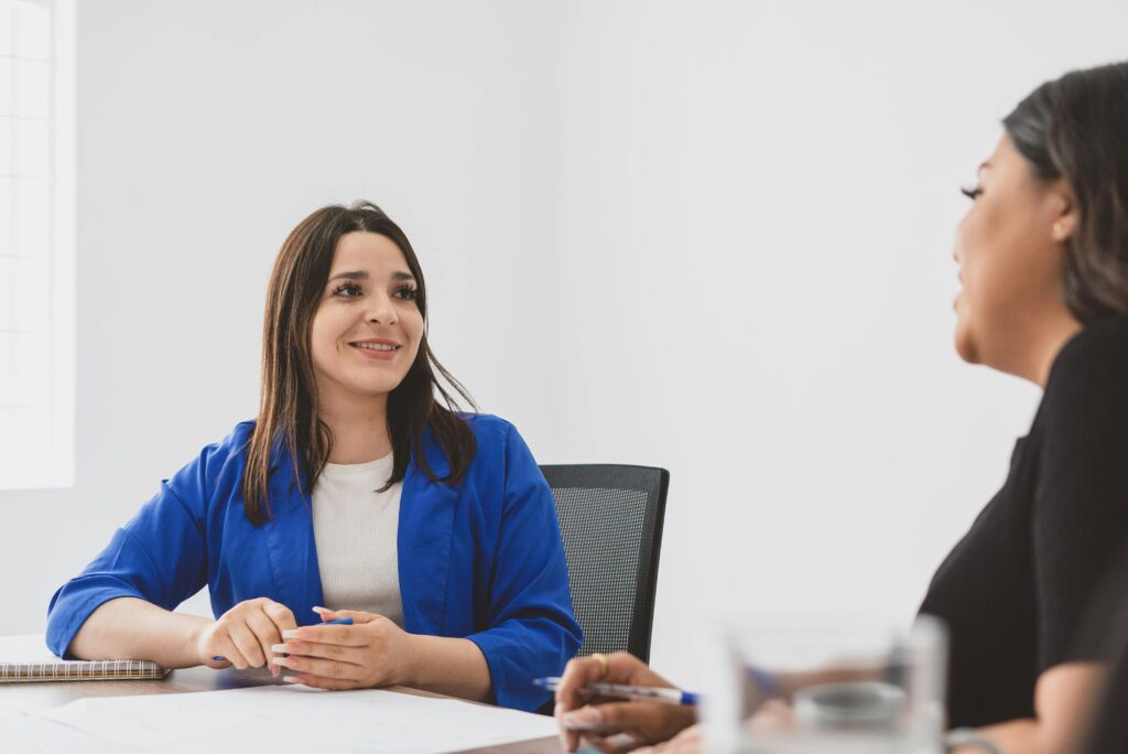Two women happily engaged in a business meeting in a bright office.